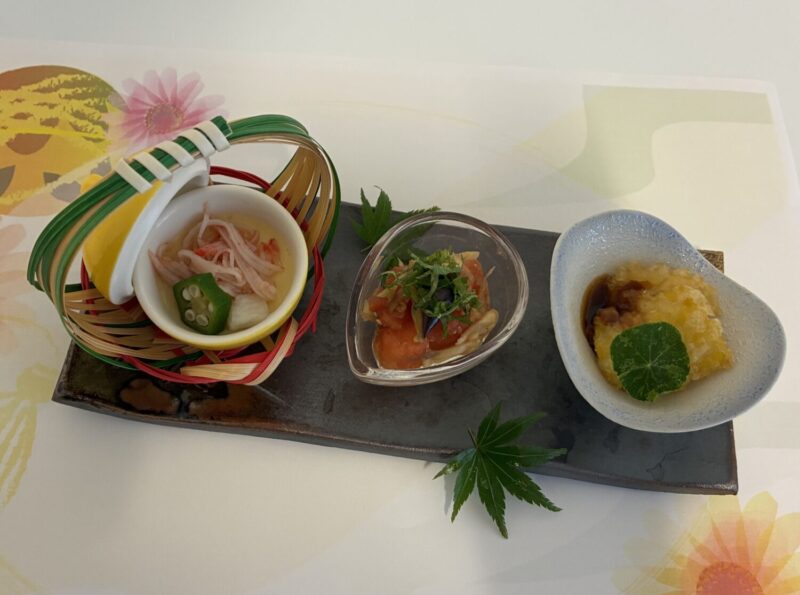 介護施設の食事。彩りよく盛り付けた複数の小鉢が黒いプレートに配置されている。